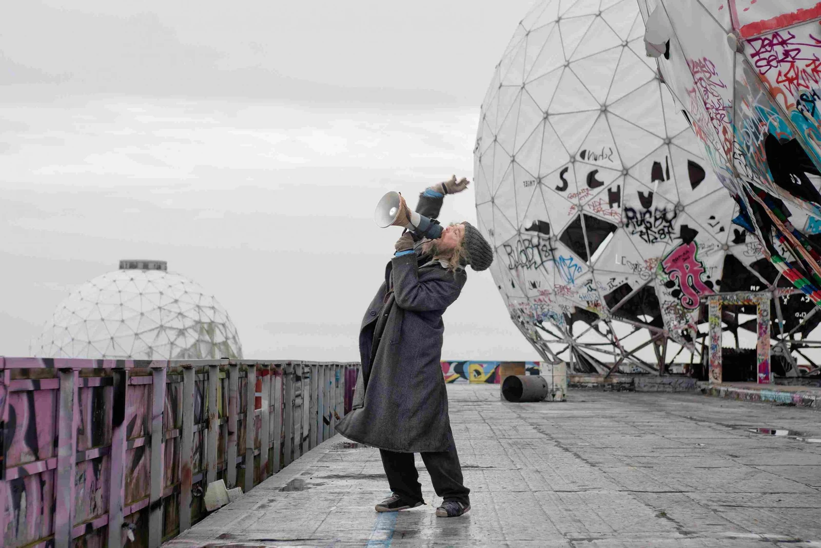 Film still from Julian Rosefeldt’s Manifesto, showing a figure on a graffiti-covered rooftop.
