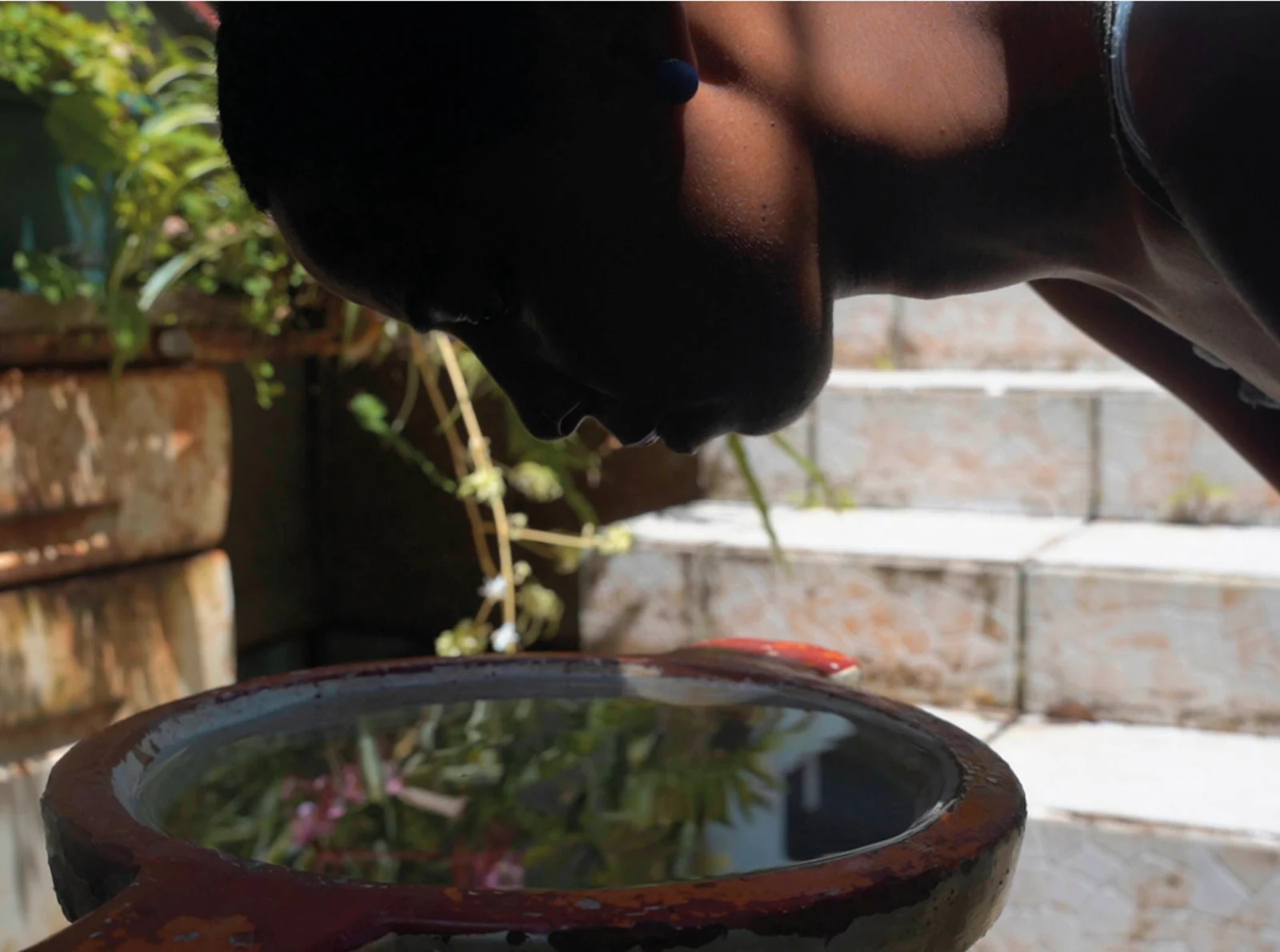 A still from Minia Biabiany’s work, showing a figure leaning over a bowl, for Nuestras escuchas.