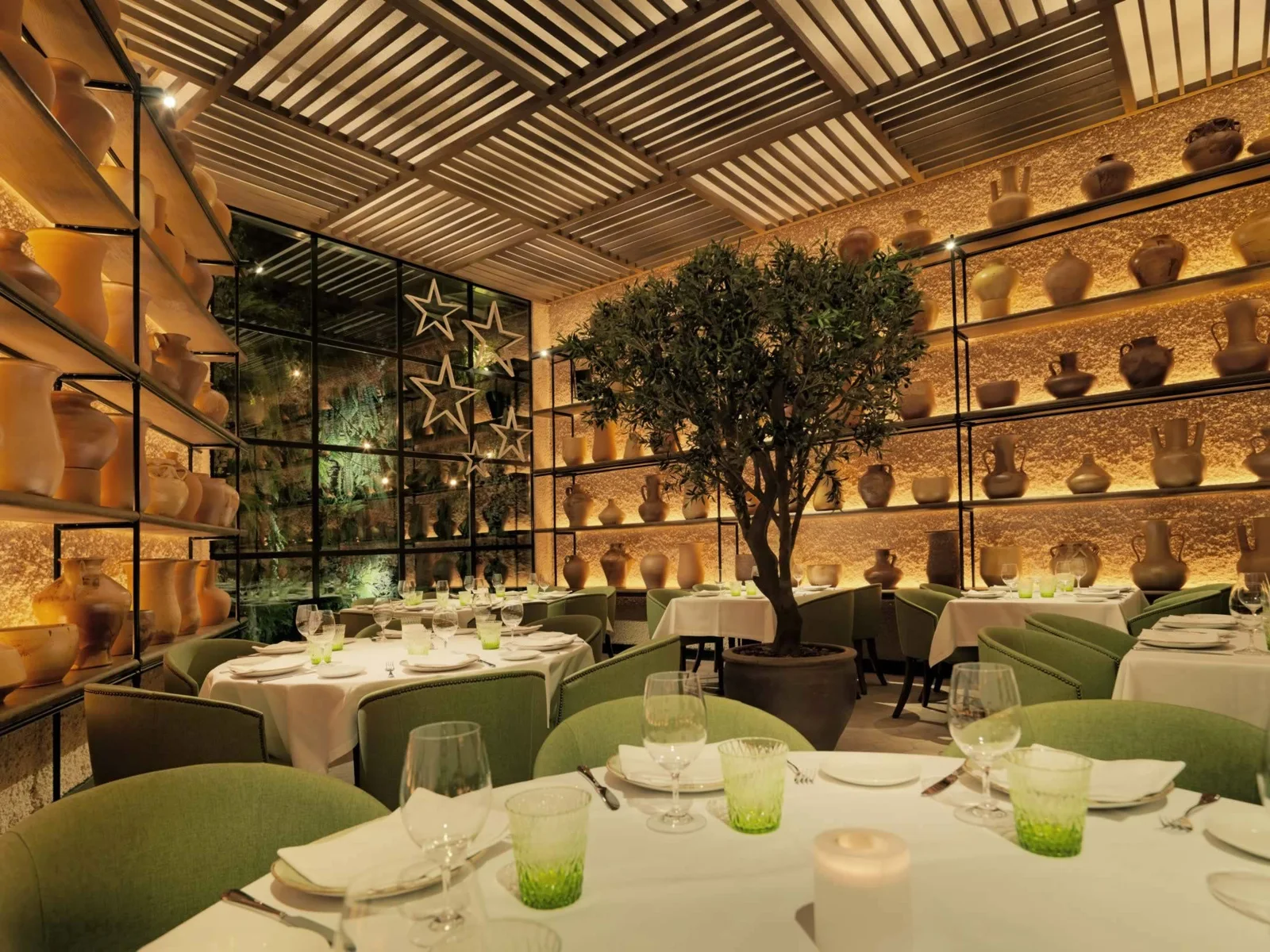 The dining room with green chairs and a planted centrepiece at Bar Cañete