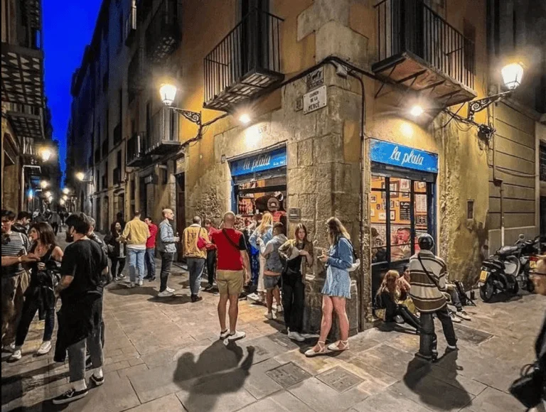 Guests outside the warmly illuminated corner bar at La Plata