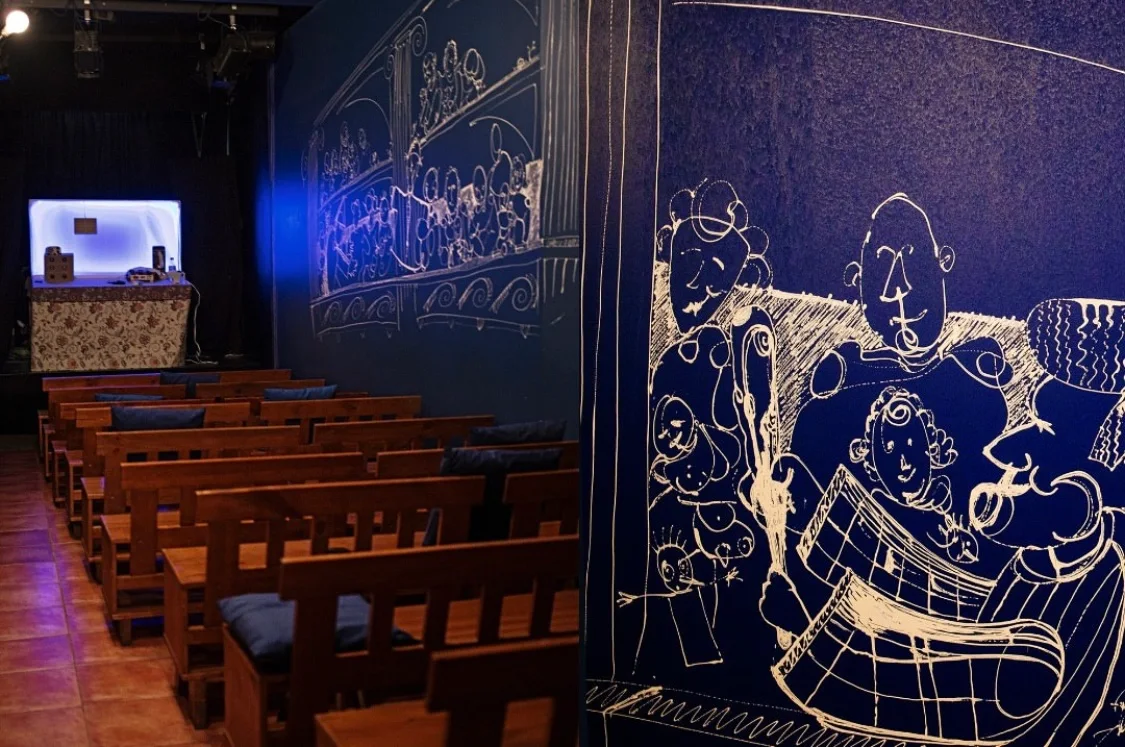 Wooden theatre benches beside illustrated walls at La Puntual