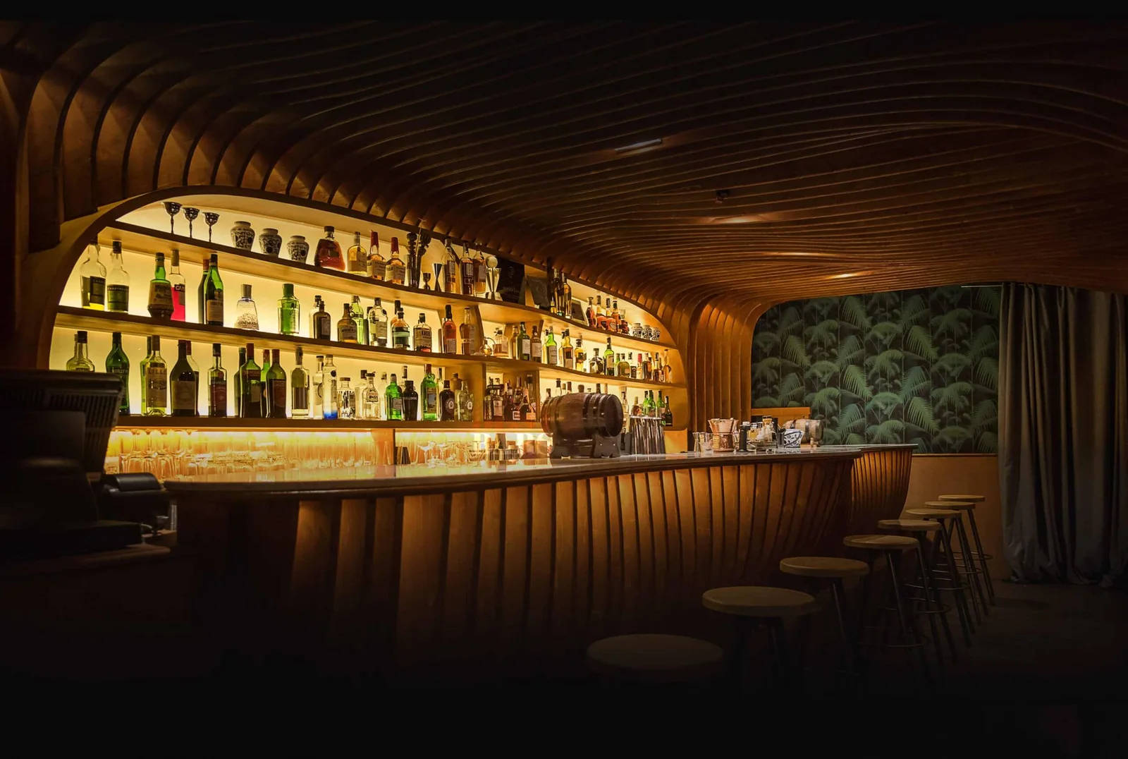 The curved timber bar and illuminated bottle display at Paradiso