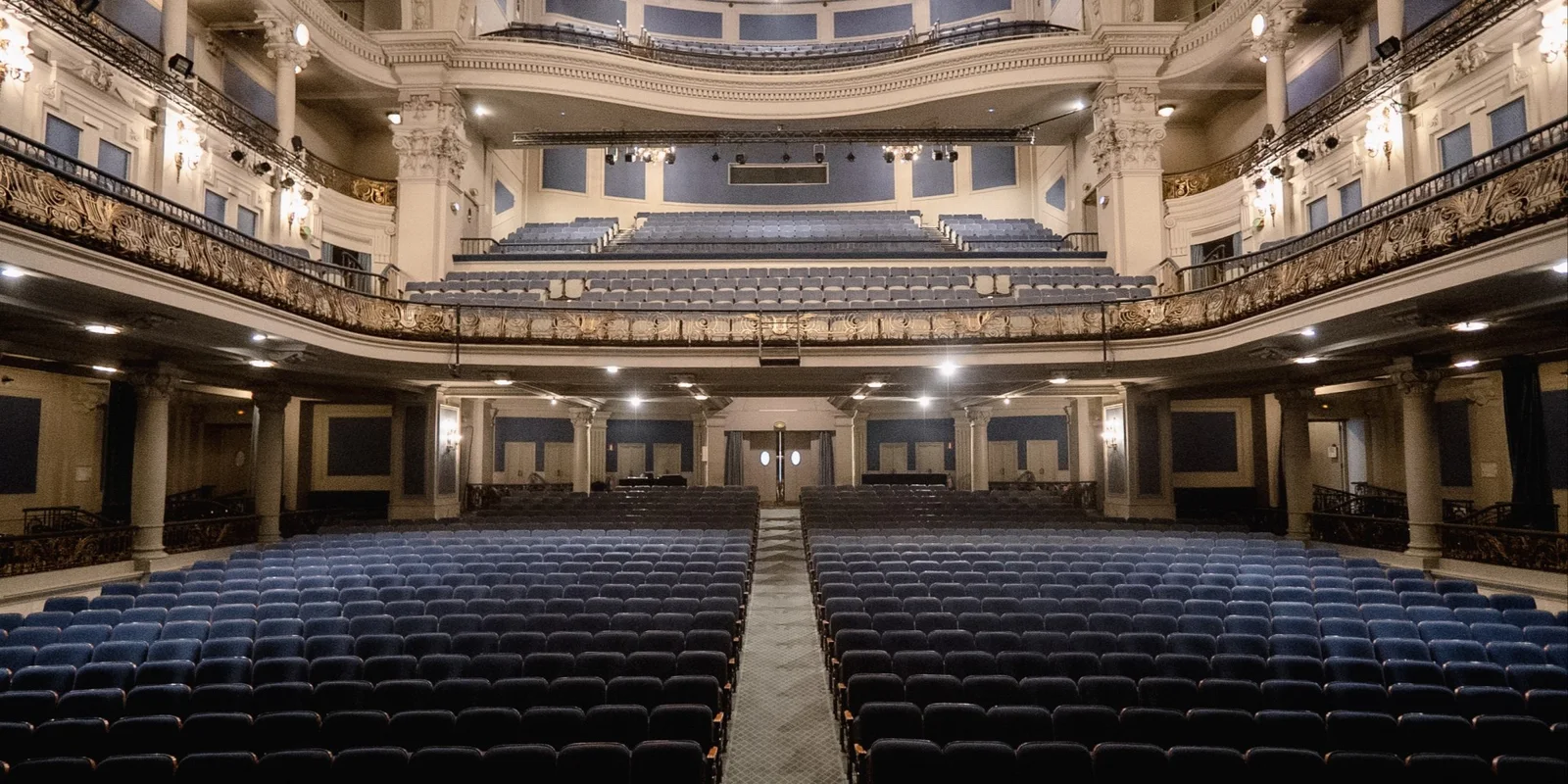Blue theatre seats below ornate balconies at Teatre Coliseum