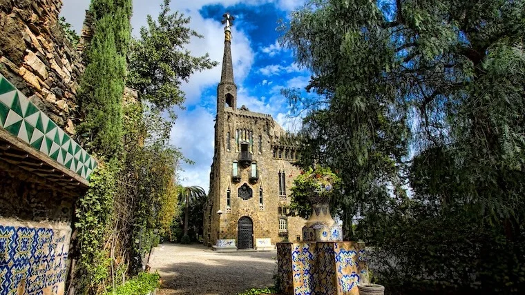 Torre Bellesguard: gaudí-designed stone tower seen through the trees and mosaic-lined gardens