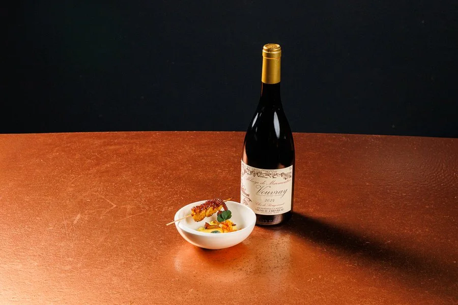 A bottle of wine beside a small plated dish at Dae Mon