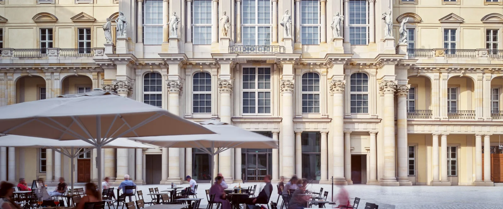 Cafe tables beneath the forum's ornate courtyard facade at Humboldt Forum