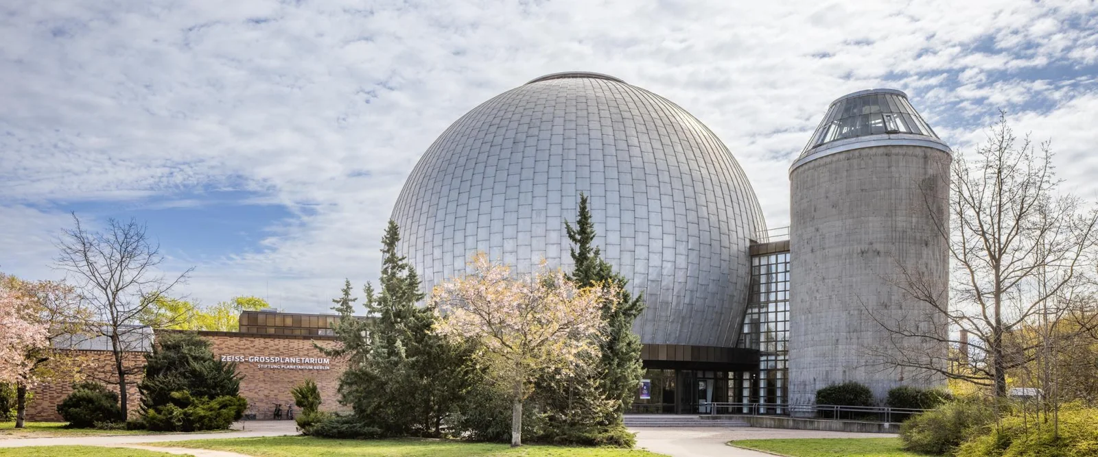 The planetarium's silver dome beside spring trees at Zeiss-Großplanetarium