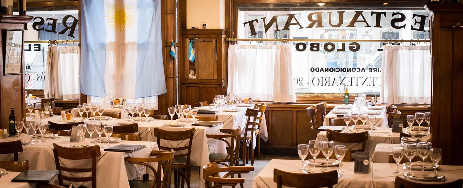 White-clothed tables beside the restaurant's lettered windows at El Globo