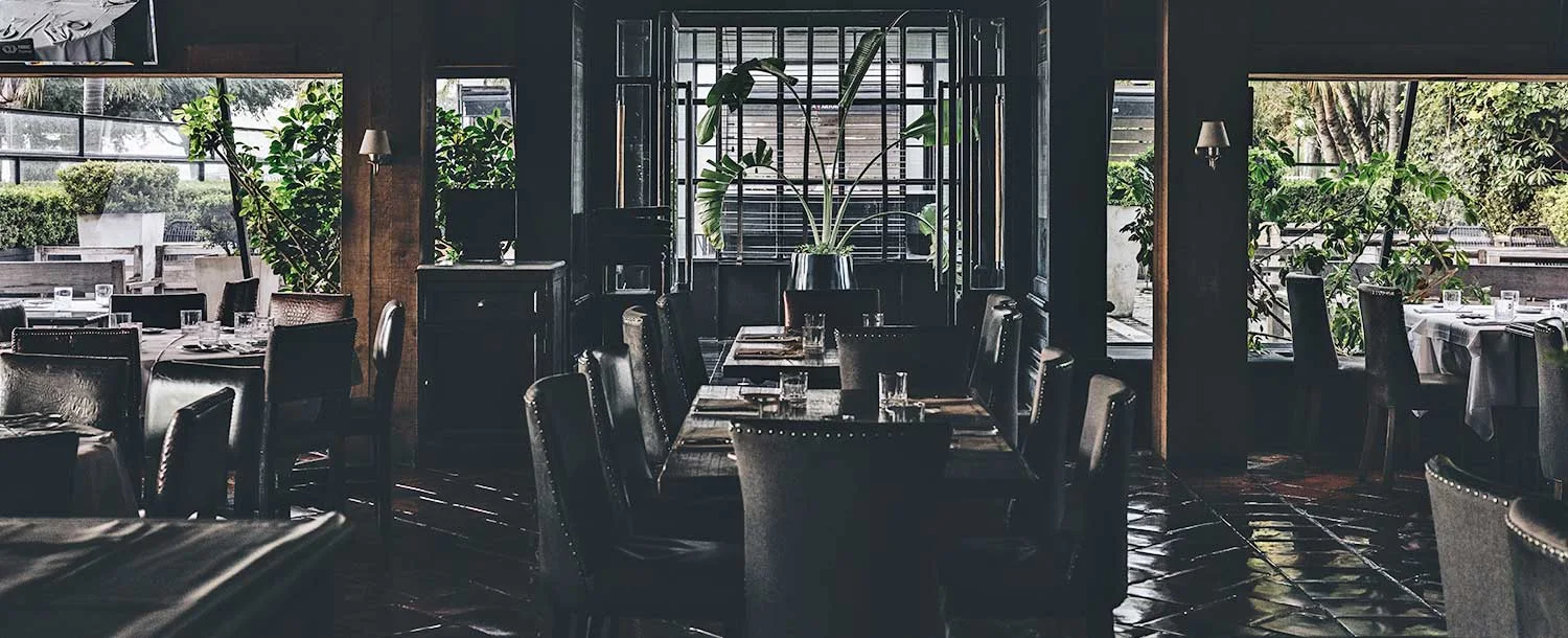 Dining tables facing wide windows and greenery at Happening Costanera