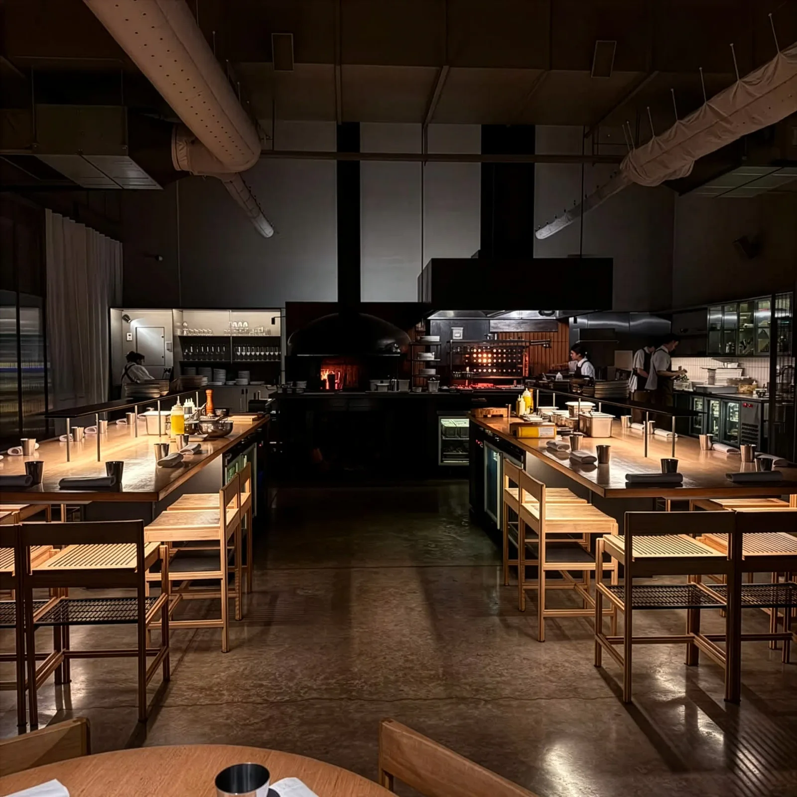 The dining room and open kitchen under warm lighting at NESS