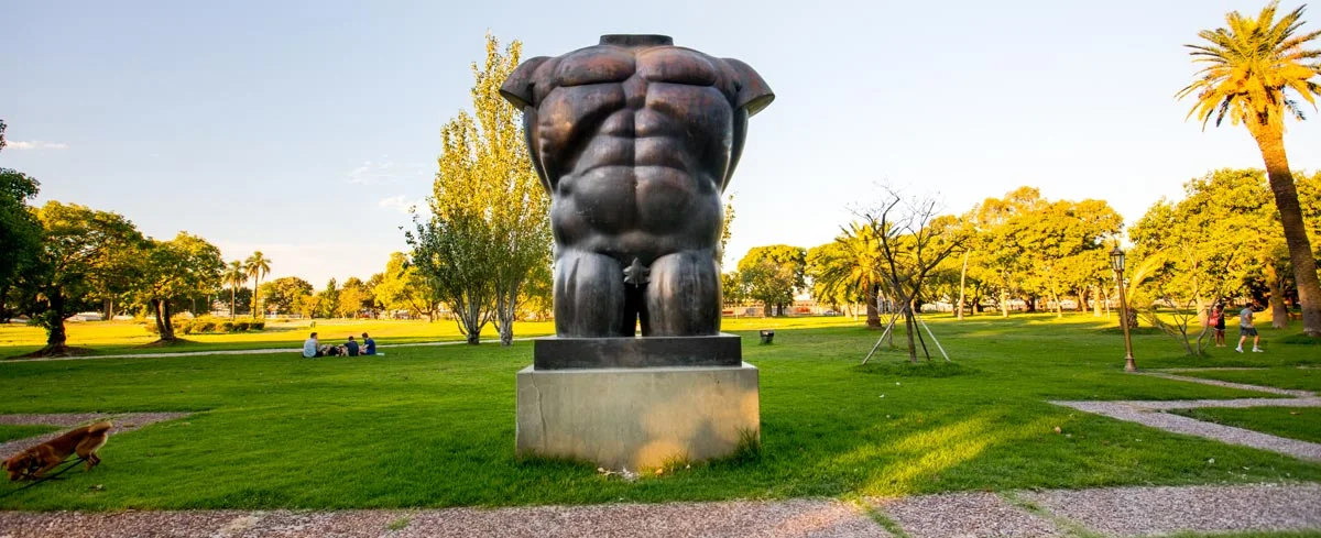 A sculpture surrounded by lawns and palm trees at Parque Thays