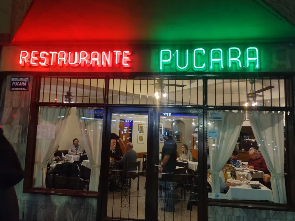 Pucará: diners behind the restaurant's red and green neon name sign