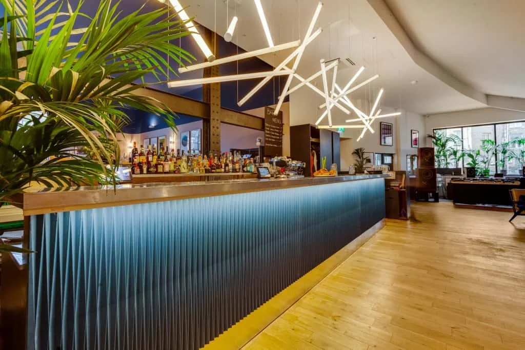 A long blue bar beneath geometric pendant lighting at EartH