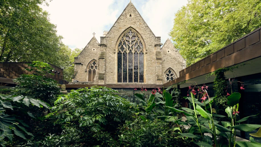 A planted courtyard beside a historic church window at Garden Museum