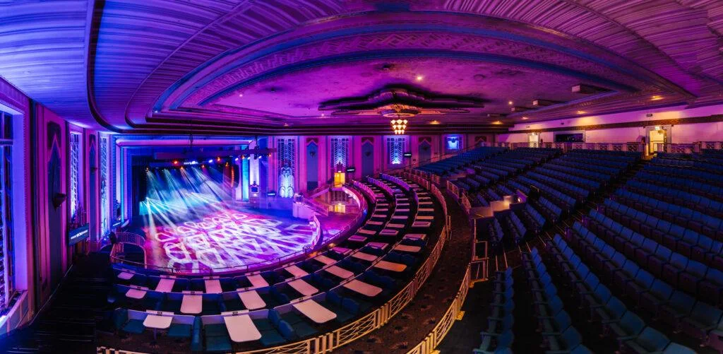 The theatre's curved balconies and floor illuminated in purple and blue at Troxy