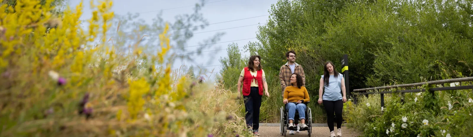 Visitors walking through a green wetland landscape at Walthamstow Wetlands