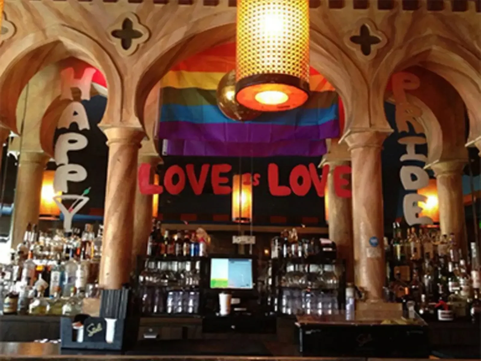 The bar counter, ornate arches and Pride flag at Akbar