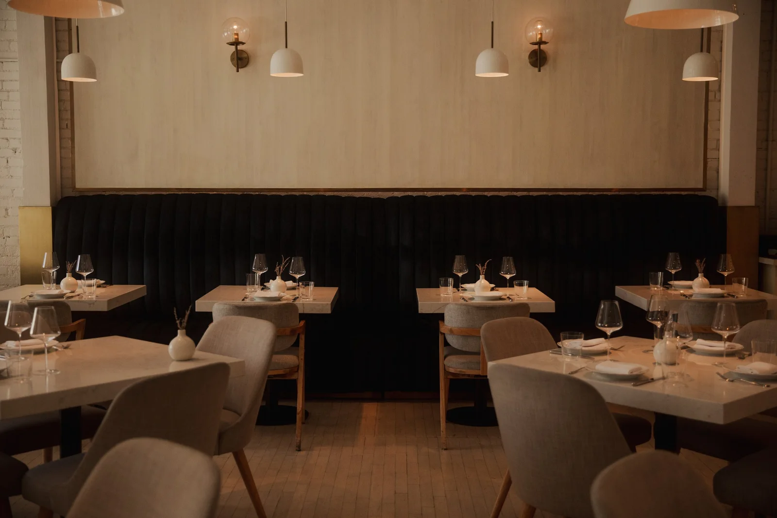 Pale banquettes and neatly set dining tables at CAMPHOR