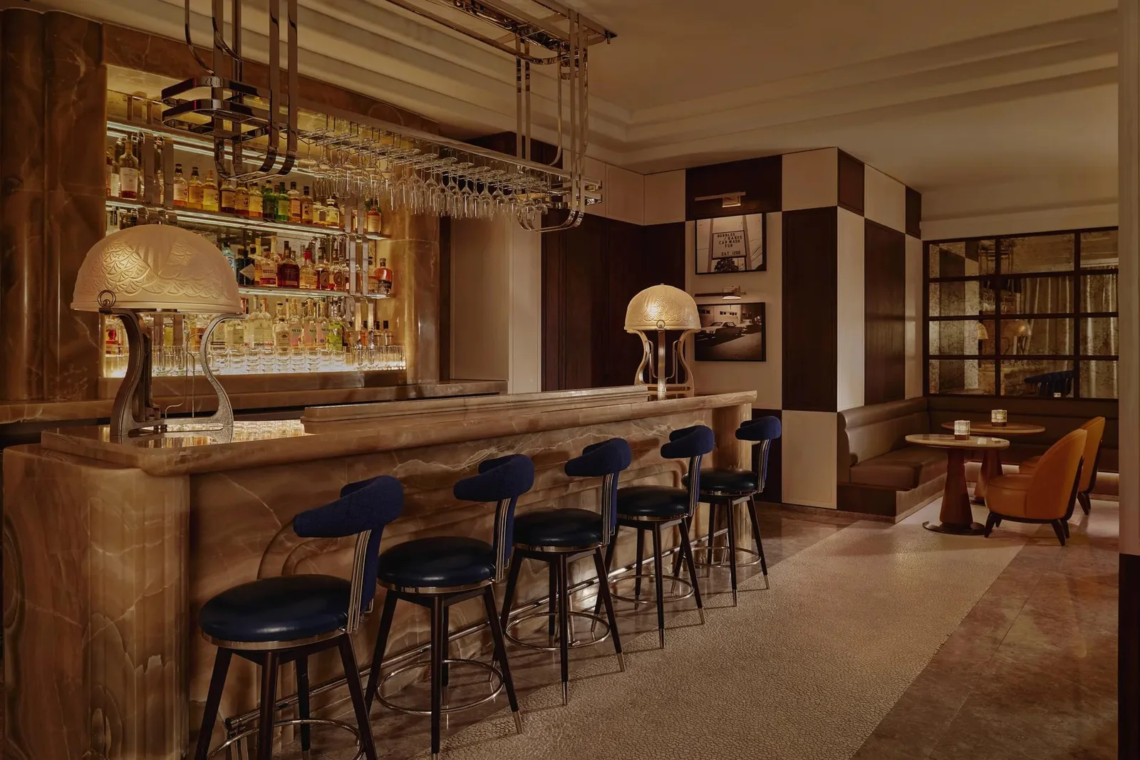 The marble bar counter and blue upholstered stools at The Maybourne Bar