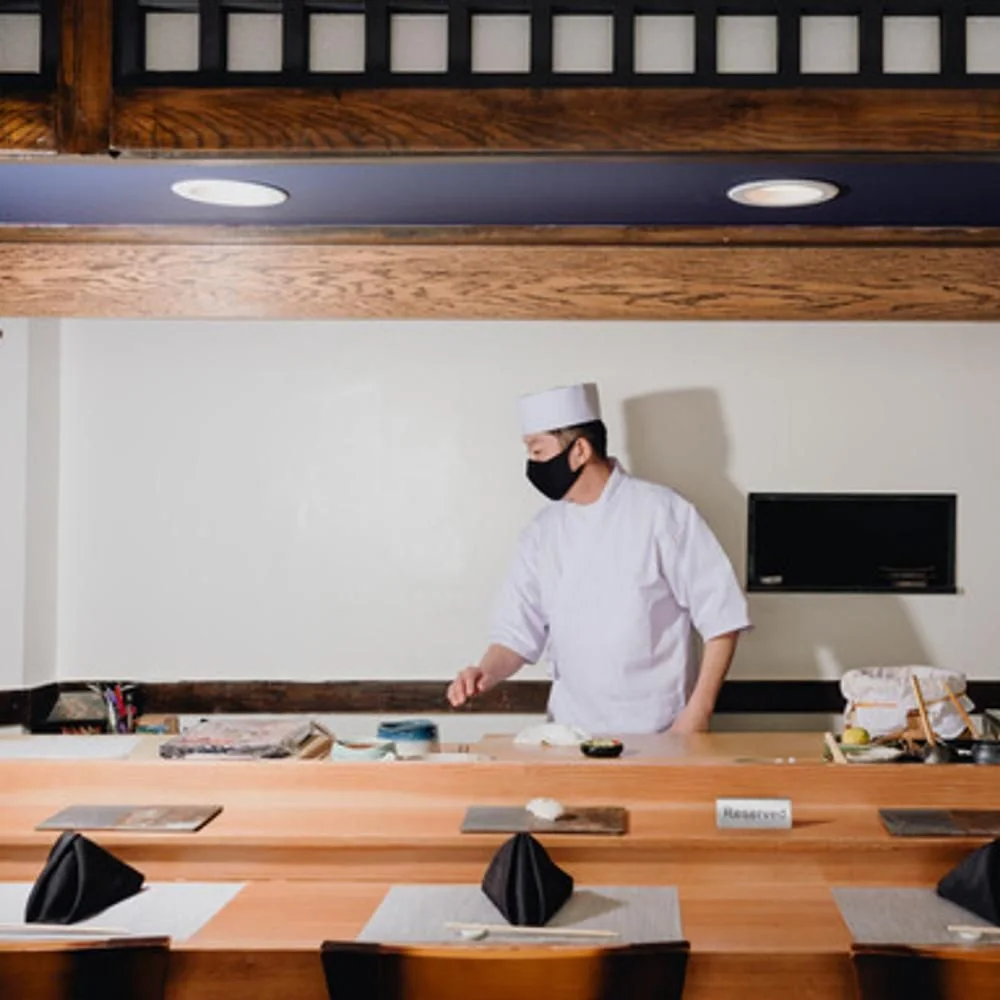 A chef behind the restaurant's wooden sushi counter at Sushi Takeda