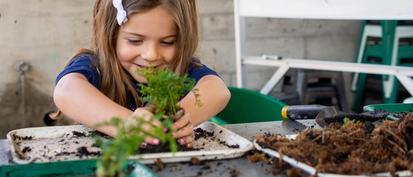 A child potting a green plant in a garden activity at Brooklyn Botanic Garden