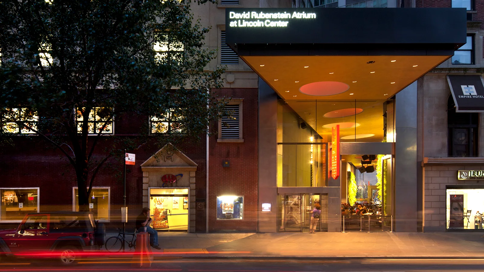 The illuminated atrium entrance from the street at David Rubenstein Atrium