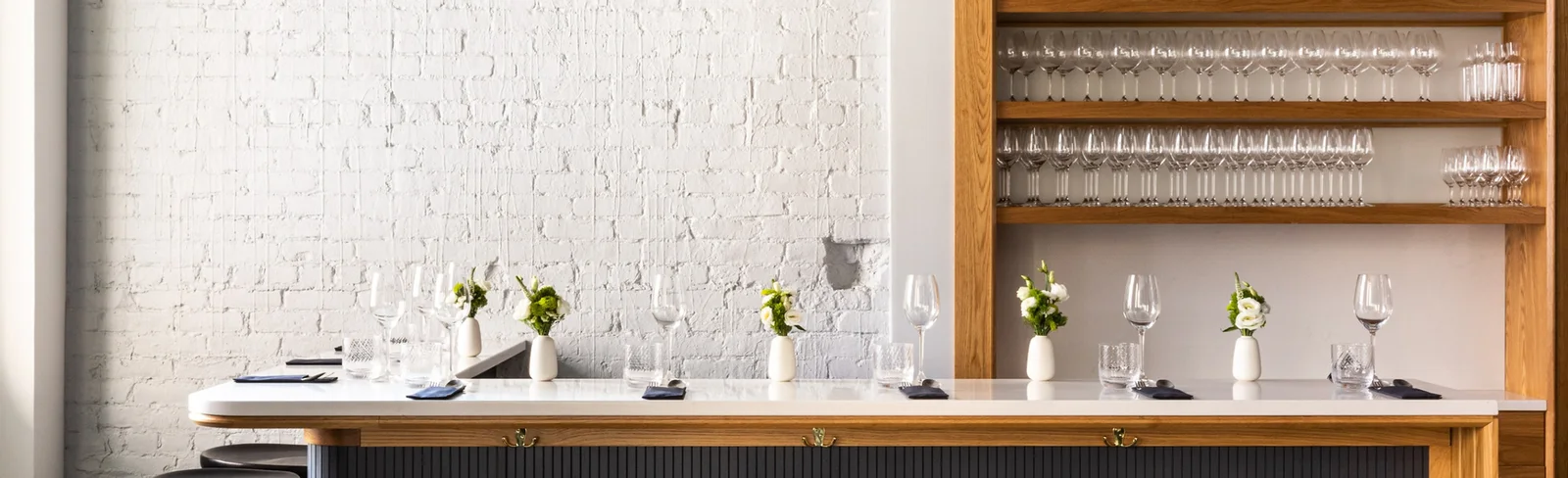 The pale bar counter and shelves of glasses at Farra