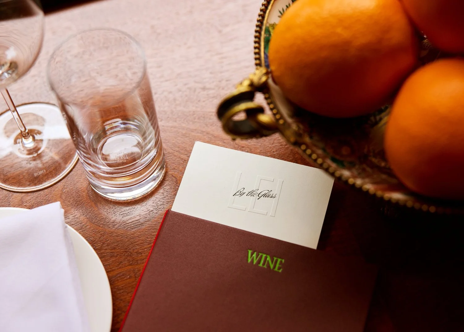 A dining table with fruit, glasses and a wine list at Lei