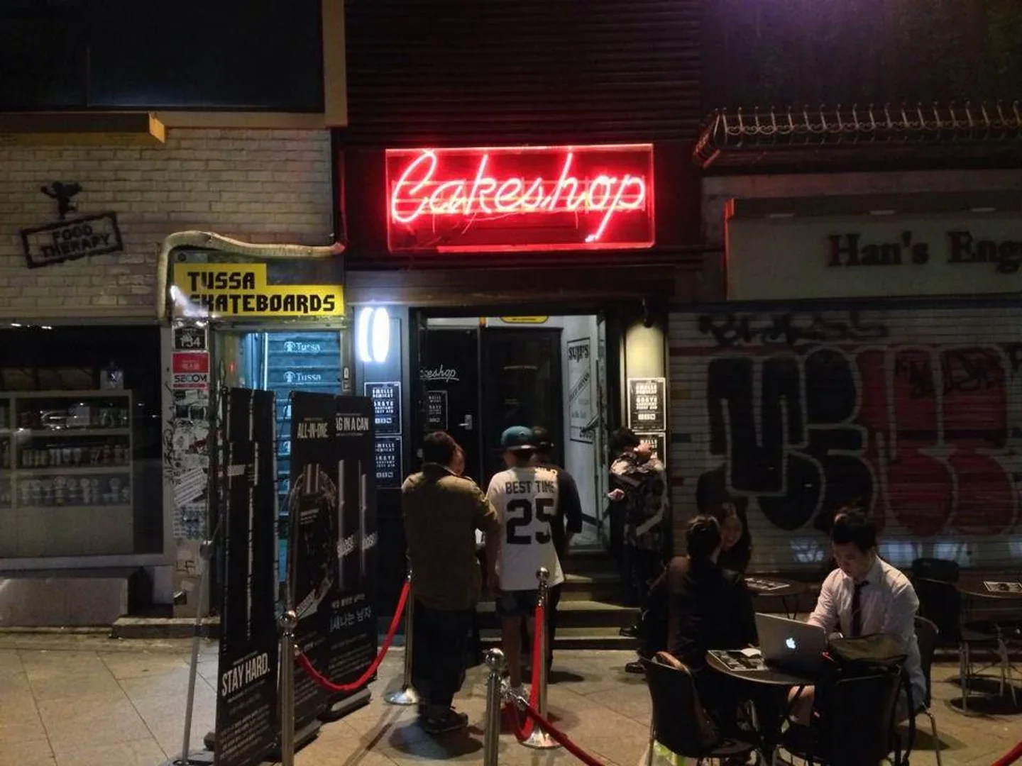 Cakeshop: the nightclub entrance and glowing Cakeshop sign after dark