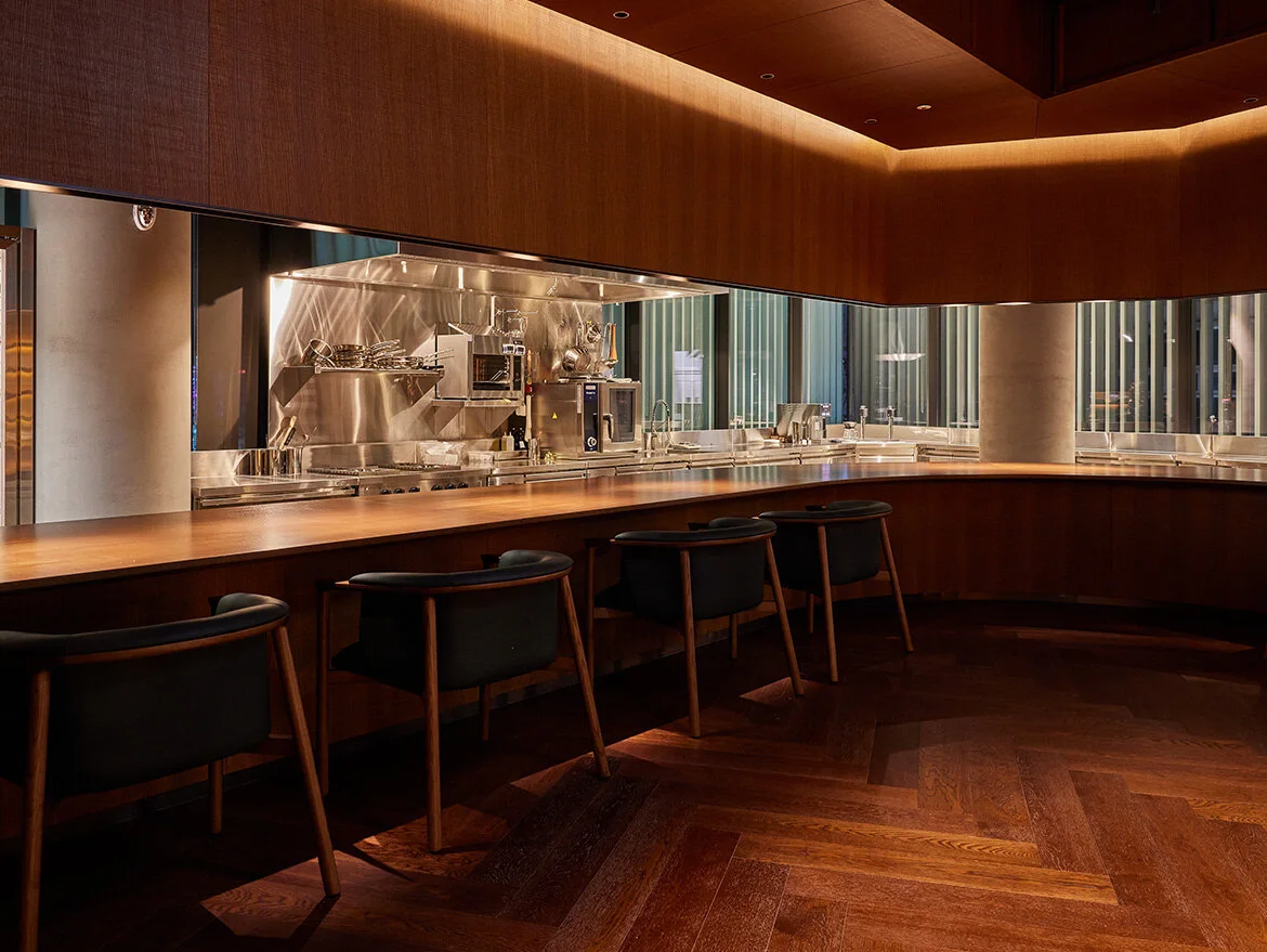 A curved dining counter in a warm-toned room at Collage