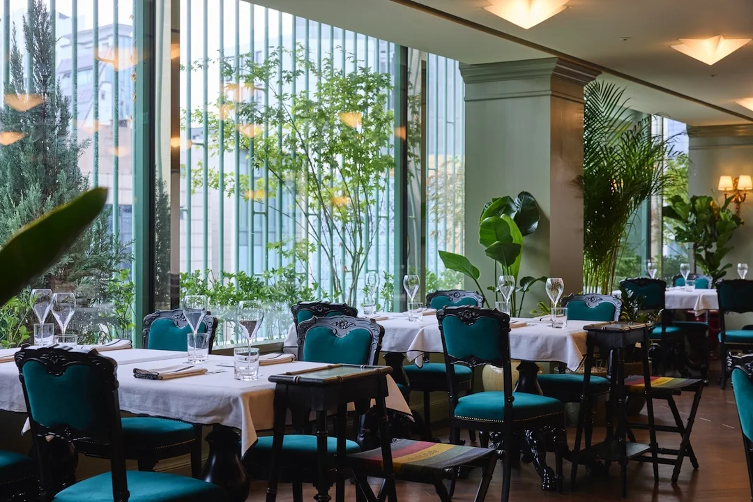 Dining tables surrounded by greenery and windows at Gucci Osteria da Massimo Bottura