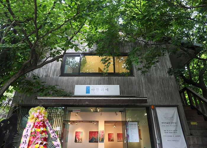 The art museum entrance beneath leafy trees at Kyungin Museum of Fine Art