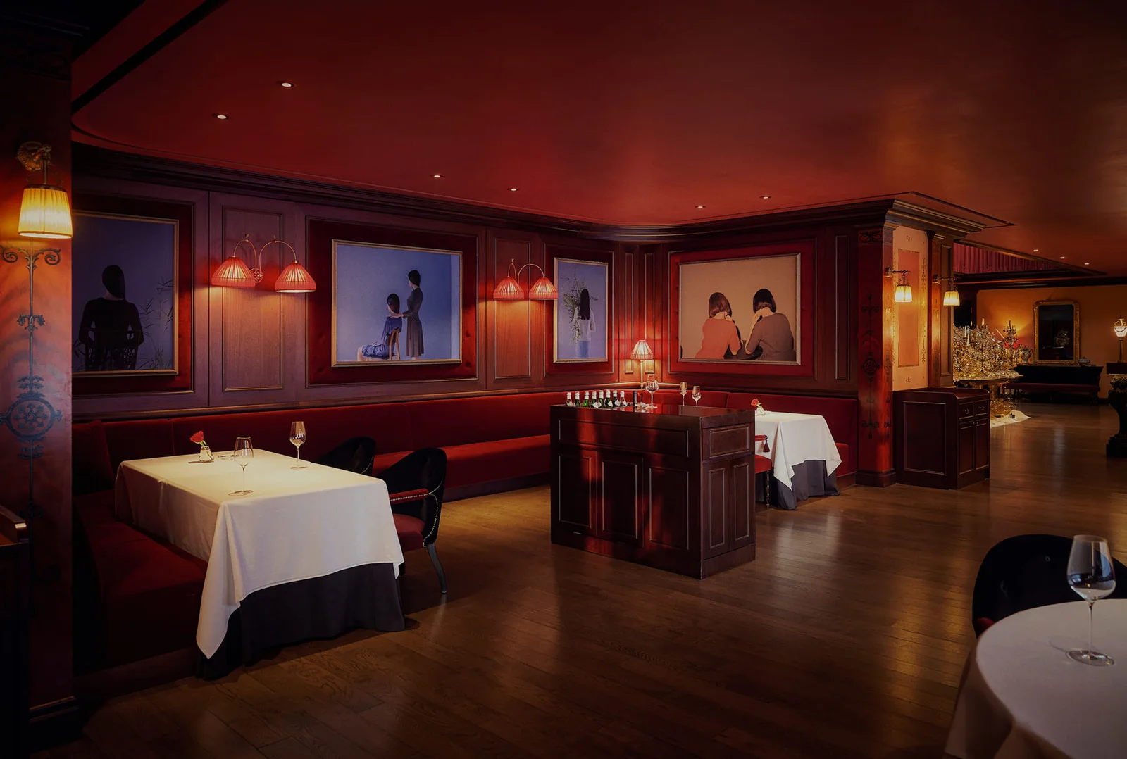 Red banquettes and framed portraits in the dining room at L'Amant Secret