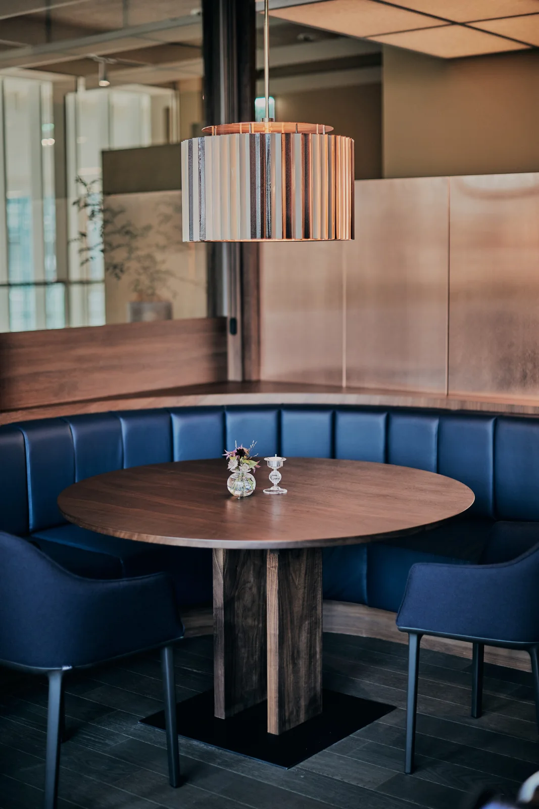 A rounded blue banquette and wooden table at Restaurant Allen