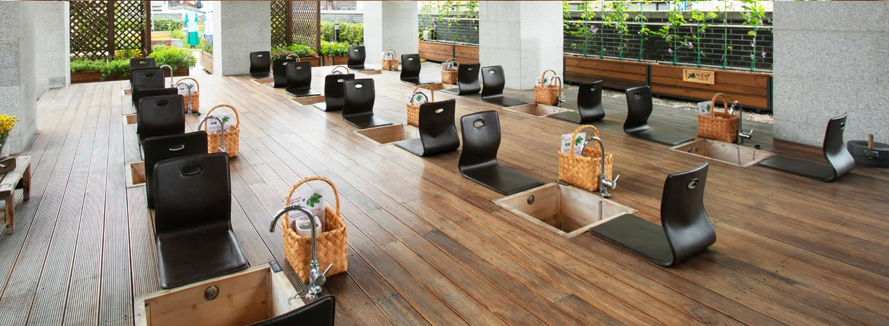 A bright terrace arranged with traditional foot-bath stations at Seoul Yangnyeongsi Herb Medicine Museum