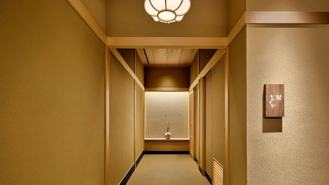 A softly lit entrance corridor with timber screens at Sushi Kanesaka