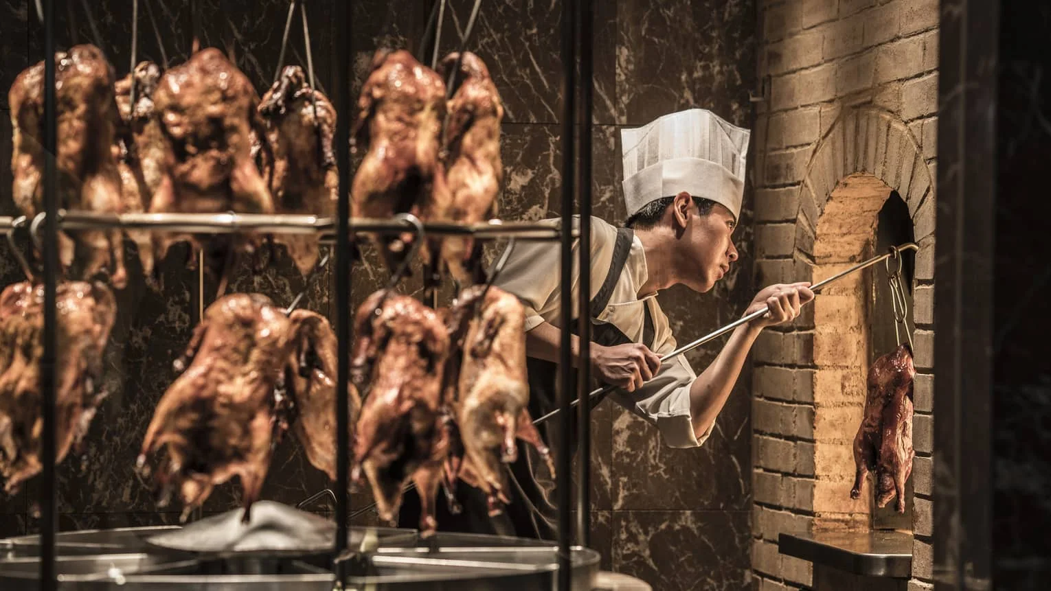 A chef tending the hanging roast ducks at Yu Yuan