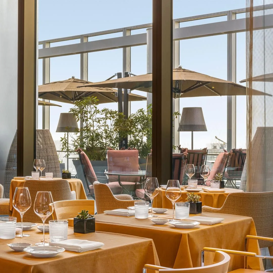 Sunlit tables beside the restaurant's terrace windows at Il Ristorante - Niko Romito
