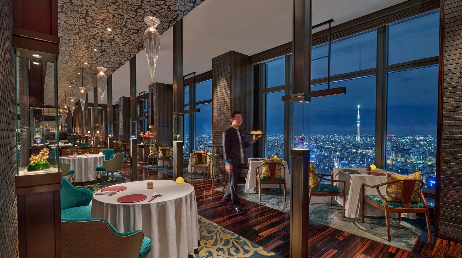 A dining room with tall windows overlooking the city at Sense
