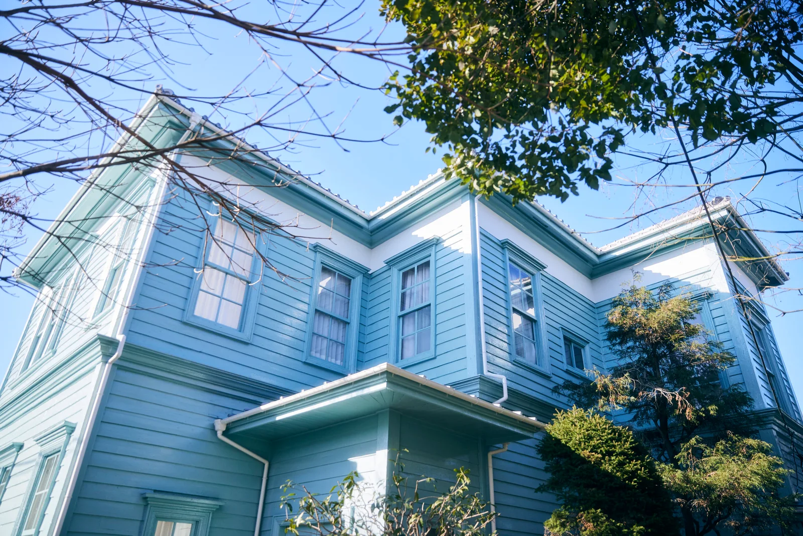 The Former Residence of Theodora Ozaki: the pale-blue historic house framed by green trees